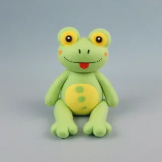 A cute felt-cloth frog with bright green and yellow colors, full-body view, wide shot, feet visible, on a plain light blue background, with a smiling face and big round eyes, made of soft and fluffy felt material, in a sitting position with its legs folded under its body