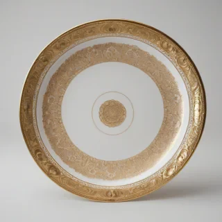 A gold gilded serving platter with intricate details, ornate patterns, and a wide rim, on a plain white background, full-body view, with the platter facing directly forward, and the lighting is soft with a slight warm glow, in the style of luxurious fine dining, with high level of detail and realism, on a plain white background, even lighting 
