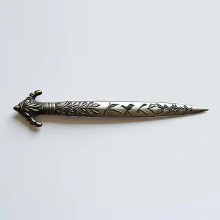 A silver spear with etchings of plants and birds on it