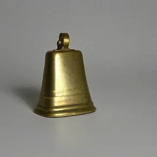 tarnished gold cow bell, bright lighting, on a plain white background, even lighting