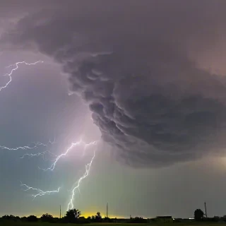 Beautiful photograph of of a yellow sky with purple, black, blue, and green thunder clouds with bright flashes visible within the storm to show lightning