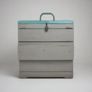A large, brutalist-style chest, made of rough, unfinished concrete, with a metallic aquamarine-colored handle, in a wide shot, with the chest centered, on a plain white background, with a soft, diffused light, and a subtle gradient to enhance the brutalist architectural style, full-body view, with the chest's feet visible
