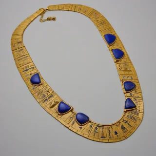 A gold Egyptian necklace with intricate hieroglyphic details and lapis lazuli stones, in a wide shot, full-body view, on a plain white background, with a soft, warm lighting and a slight sheen to the gold, in the style of ancient Egyptian jewelry, on a plain white background, even lighting 