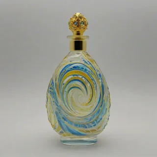 Fancy, decorative, multicolored glass perfume bottle with swirling patterns of blue and gold, on a plain white background, even lighting