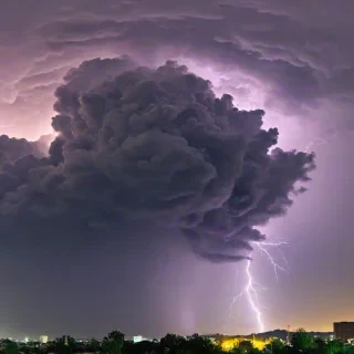 Beautiful photograph of of a yellow sky with purple, black, blue, and green thunder clouds with bright flashes visible within the storm to show lightning